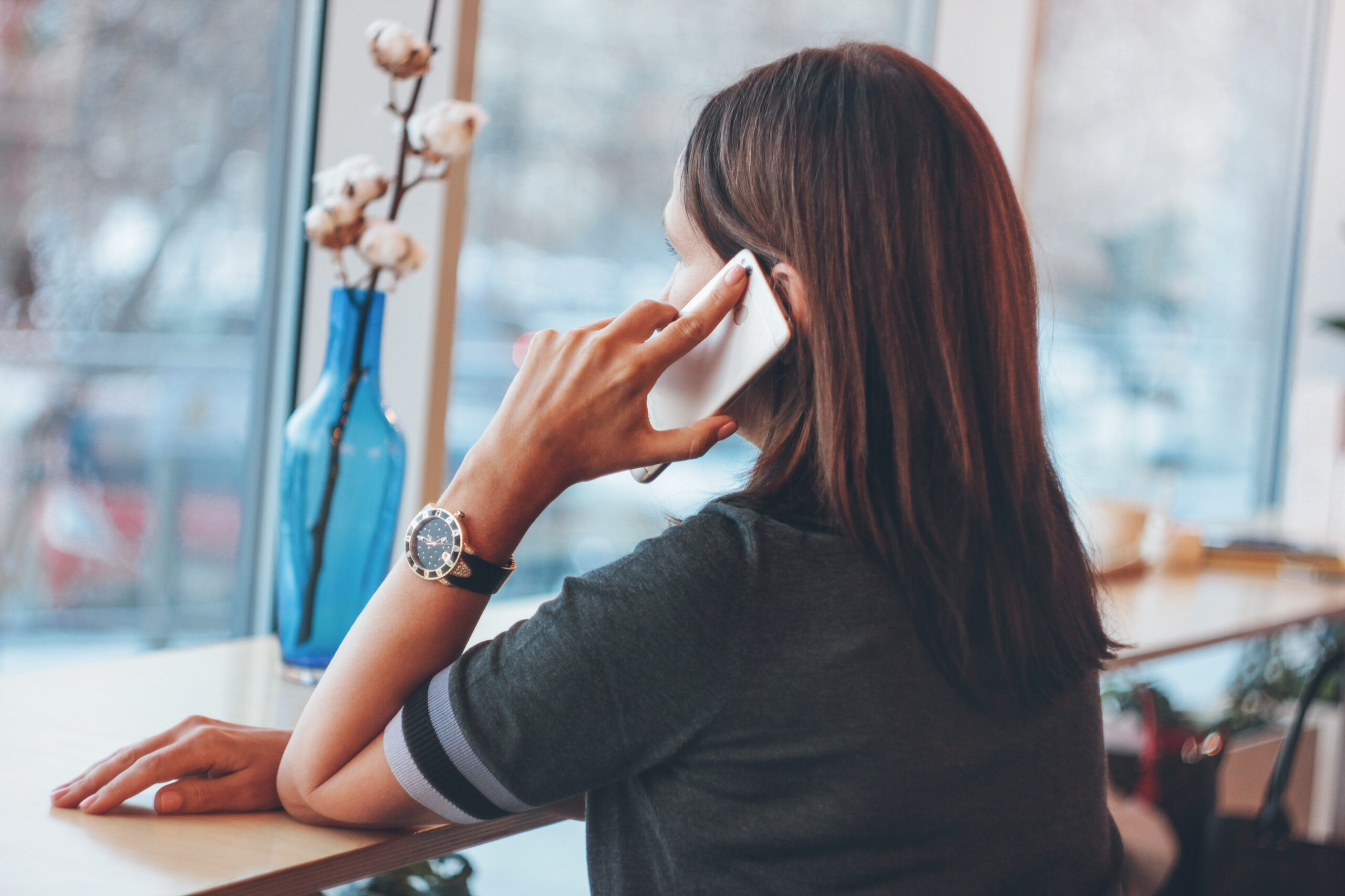 Beautiful middle-aged adult woman smiling and talking on the phone in cafe